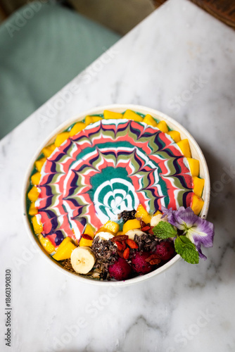 Obraz na płótnie Top-down view of a singular multicoloured marbled smoothie bowl on a white café table