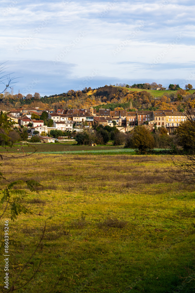 Obraz premium Historic center of Carbonne within a bend of the Garonne River, dominated by hillsides at the end of autumn
