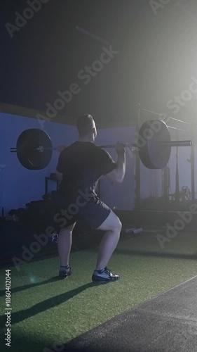 Man exercise deadlift with over head press weightlifting under spotlight in gym