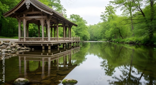Tranquil wooden pavilion reflects beautifully on a calm river surrounded by lush green forest.