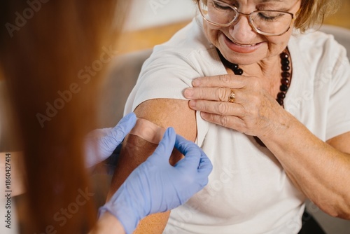 фотографія Senior woman receiving vaccination, nurse applying bandage on arm