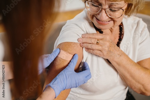 Photos Senior woman receiving vaccine with medical professional applying plaster