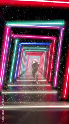 Woman walking through vibrant neon tunnel with colorful lights
