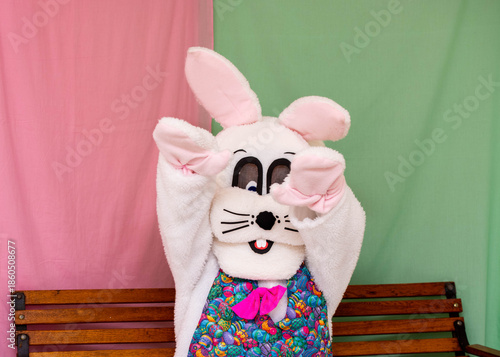 Fotografia A person dressed up in a funny but slightly creepy Easter bunny costume sits on a bench and waves to kids during a holiday event