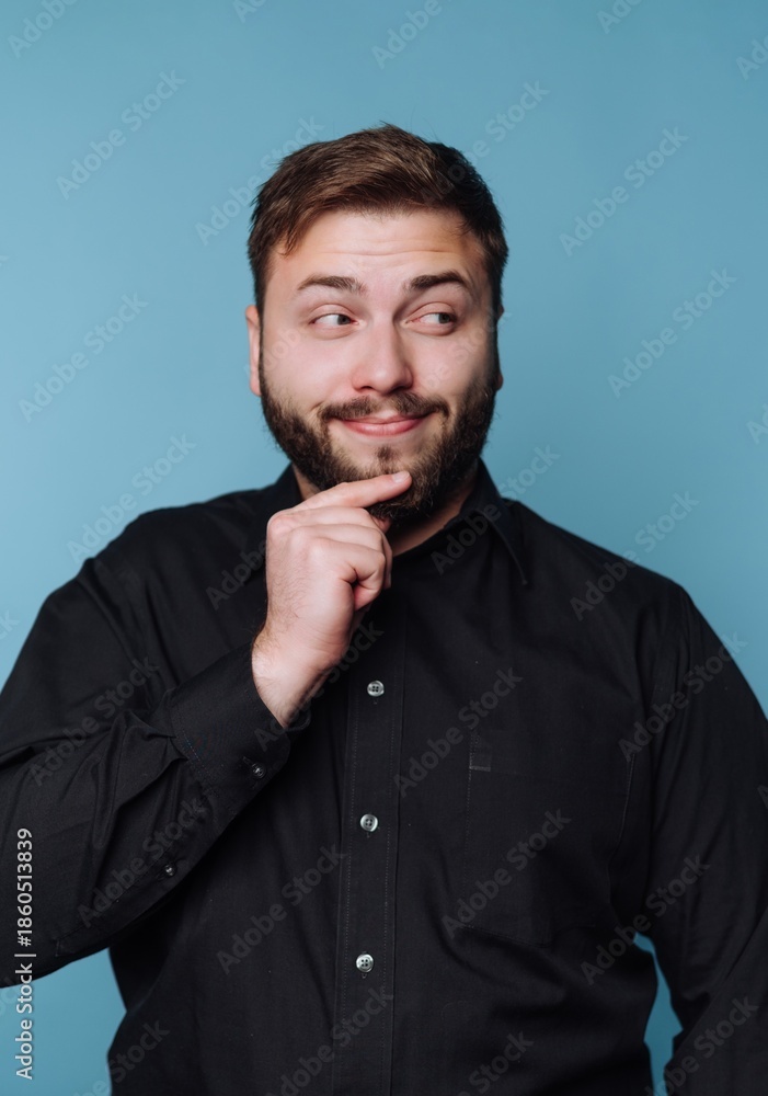 Obraz premium Man in black shirt with thoughtful expression against blue background.
