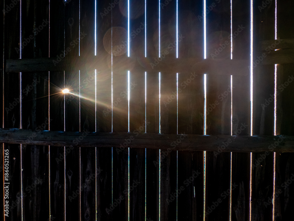 Fototapeta premium Sonnenstrahlen dringen durch die Ritzen einer alten Bretterwand