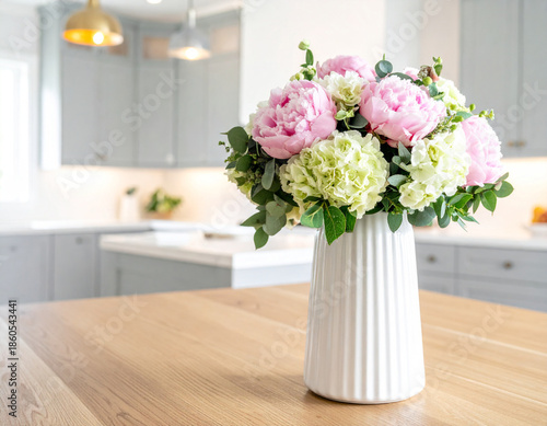 Beautiful bouquet of pink peonies and green hydrangeas in a white vase on a wooden table