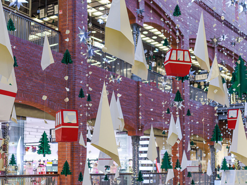 Hanging Christmas decorations and ornaments inside a shopping mall interior. Concept of festive retail background for holiday shopping, seasonal marketing, commercial design.
