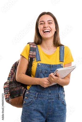 Woman smiles while holding a notebook in an isolated setting. She wears a yellow shirt.