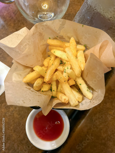 French fries served on a paper lining on a table with ketchup