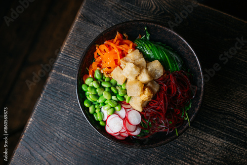 A bowl of food with a variety of vegetables including carrots, radishes