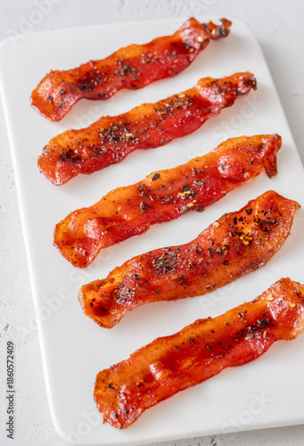 Billionaire bacon strips glazed with pepper and chili flakes on minimalist plate