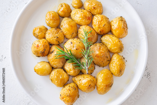 Oven baked baby potatoes seasoned with herbs served in white ceramic bowl