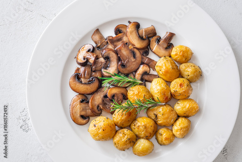 Roasted baby potatoes with sauteed mushrooms and rosemary on minimalist white plate
