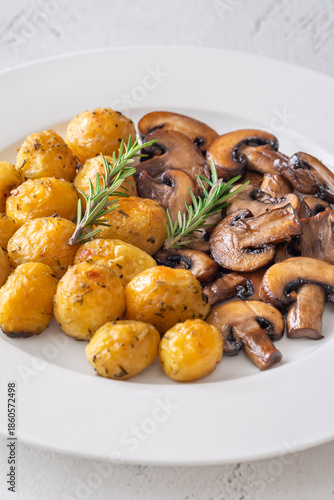 Roasted baby potatoes with sauteed mushrooms and rosemary on minimalist white plate