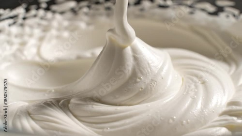 Close-up of whipped cream swirling in a mixing bowl with beater attachment in use for dessert preparation