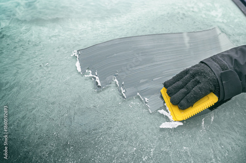Person kratzt Eis von Windschutzscheibe – Symbol für Wintervorbereitungen und Autofahren im Winter
