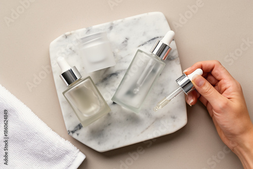 Skincare bottles and dropper on marble flatlay.