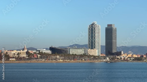 Wide panoramic view of Barcelona coastline skyline with modern buildings and calm Mediterranean sea, clear blue sky and urban beach cityscape, travel destination background with copy space