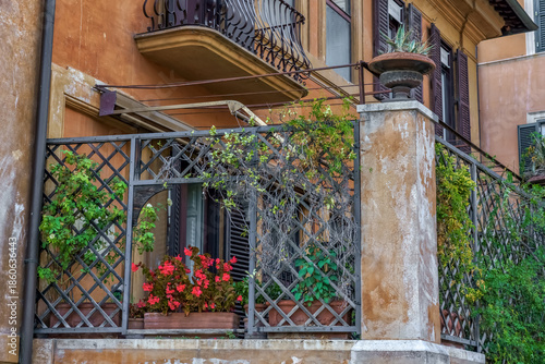 Rome, Italy. Beautiful balcony adorned with vibrant flowers and greenery, showcasing charming Italian architecture in a picturesque urban setting