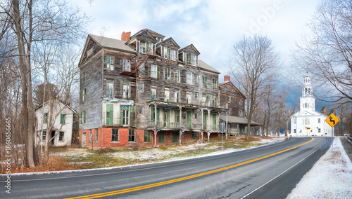 Abandoned hotel on deserted highway with threatening storm clouds and church in background