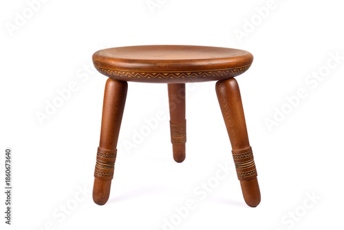 Handcrafted vintage three-legged carved wooden stool isolated on the white background. Selective focus.