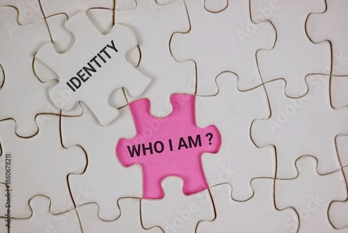 A pink puzzle piece reading 'Who I Am?' sits among white pieces labeled 'Identity,' symbolizing self-discovery and personal identity. Ideal for psychology, branding, and introspection themes.