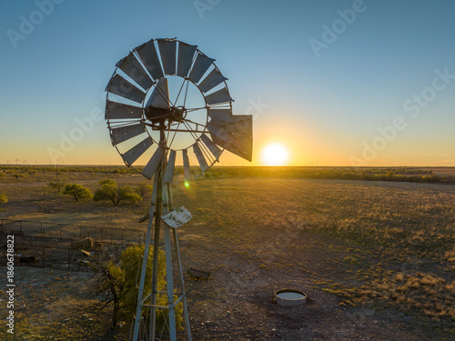 Metal Windmill In Grassy Field with Orange and Blue Sunset Sky