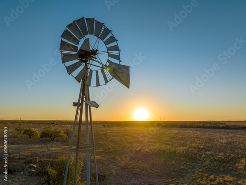 Metal Windmill In Grassy Field with Orange and Blue Sunset Sky