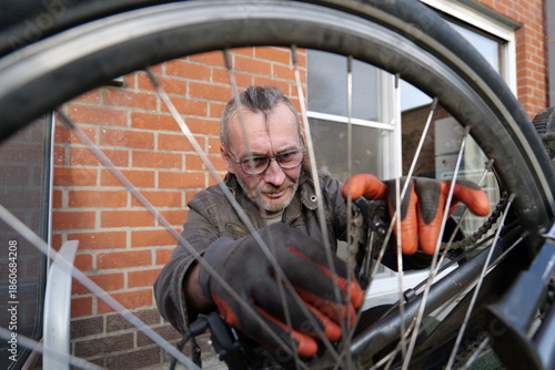 Foto Man repairing bicycle near brick building during the daytime for transportation