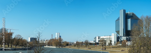 Dialogue between nature and geometry expressed in quiet riverside scene with modern architecture and bare trees. National library of Belarus in Minsk with modern glass architecture.