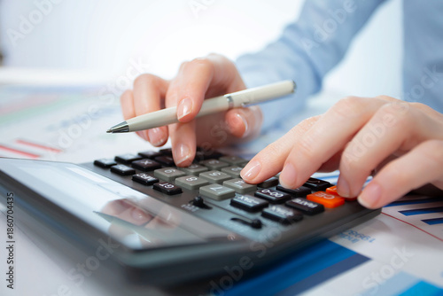 A woman works with a calculator on an annual report in the office. Close-up