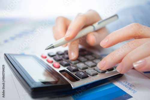 A woman works with a calculator on an annual report in the office. Close-up