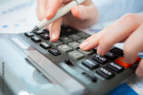 A woman works with a calculator on an annual report in the office. Close-up