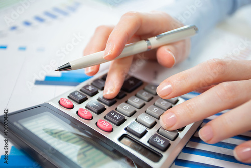 A woman works with a calculator on an annual report in the office. Close-up
