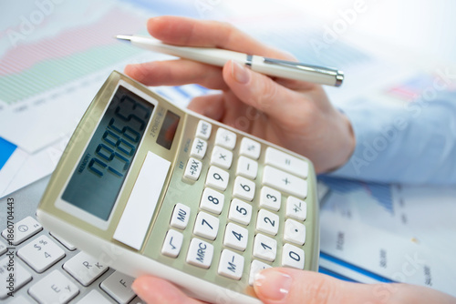 A woman works with a calculator on an annual report in the office. Close-up