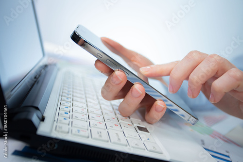A woman works with a smartphone in the office, on a report. Close-up of her hands. 	