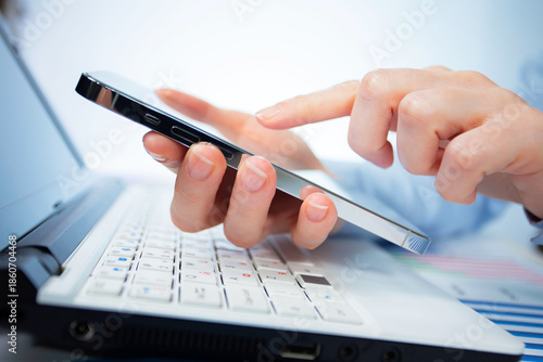 A woman works with a smartphone in the office, on a report. Close-up of her hands. 	