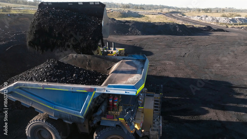 Front-end mining loader in the process of extracting and loading coal into dump trucks