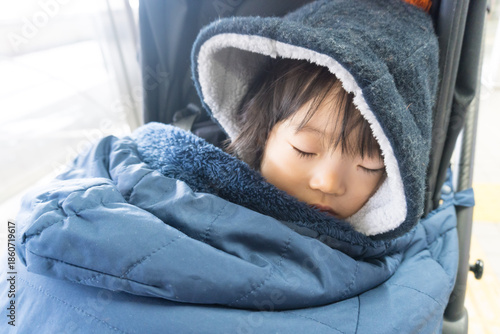 ベビーカーの寝袋に包まれた日本人の女の子の幼児