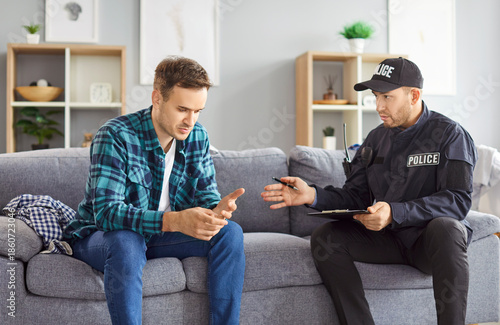 Photos Portrait of police man officer talking to witnesses making interview sitting with young man robbery victim after burglary interrogating him at home