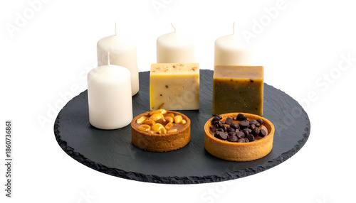 Composition of candles, soap, and tarts on a dark circular slate against black