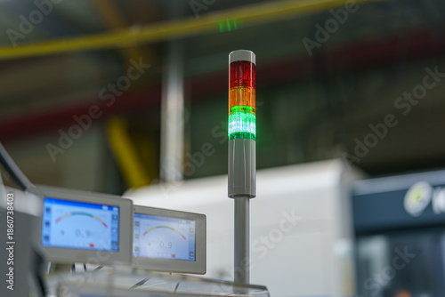 Signal tower displays lights in an industrial setting with screens showing data near the machinery during work hours