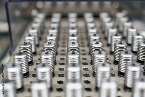 Billede på lærred Many metal objects lined up on a surface in a factory during the day