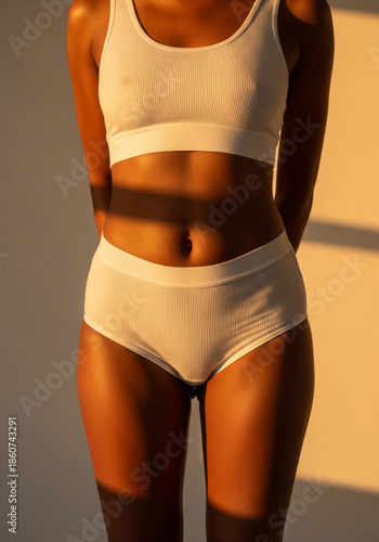 Cropped shot of a fit young woman with beautiful glossy tanned dark skin wearing a comfortable white ribbed lingerie set. 