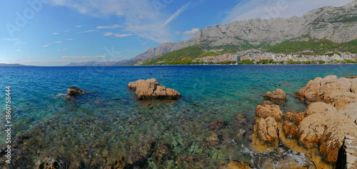 Panoramic view of the turquoise water of the Adriatic Sea and the town of Makarska, Croatia, with the Biokovo mountain in sunny summer day