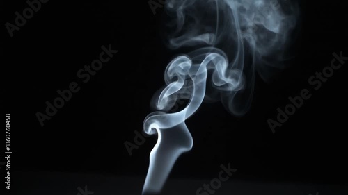 Wispy white smoke rising and swirling against a dark black background, creating abstract patterns and delicate forms.