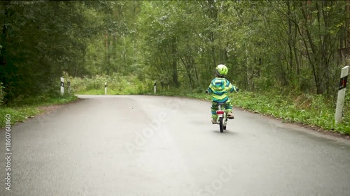 A small child, safely protected by a helmet, experiences the excitement of their first bike ride. Highlights active family life and the importance of safety in sports.