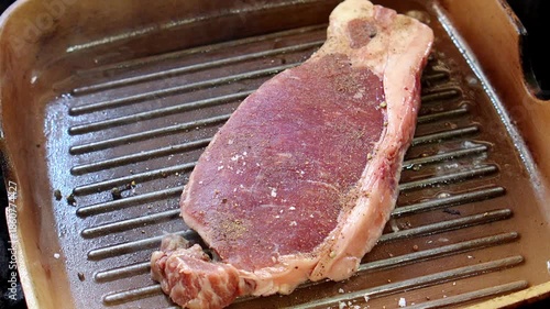 4K Seasoned raw beef steak placed on grill pan ready for cooking showing fresh marbled texture and preparation stage, Concept of culinary cooking gourmet meat butcher quality.