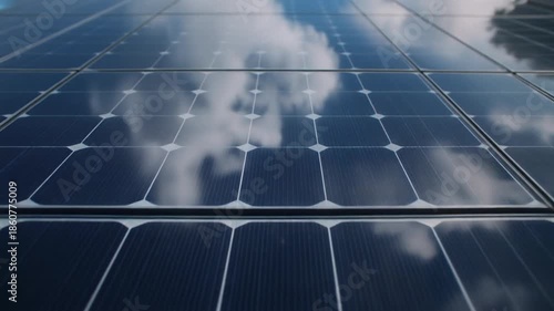 Close-up view of solar panels reflecting the sky and clouds, showcasing renewable energy technology.